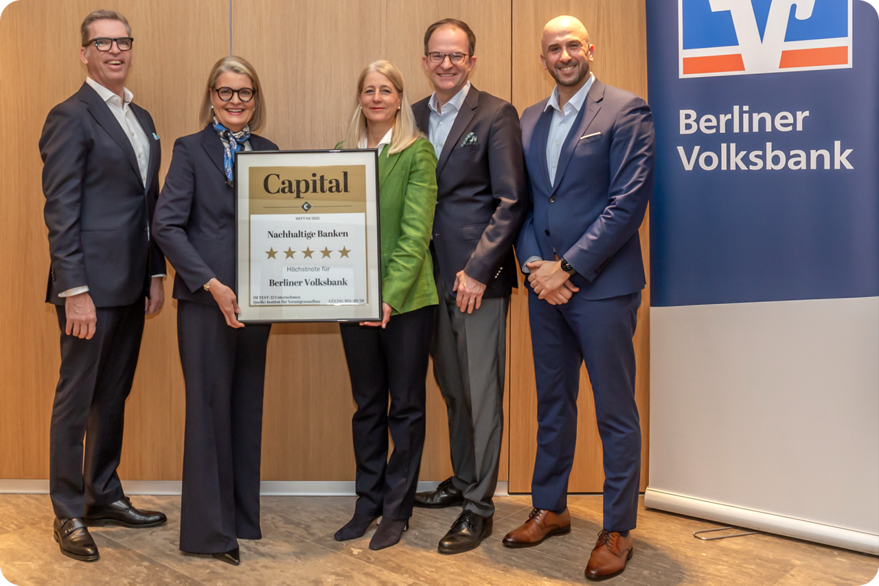 Fünf Personen stehen auf einer Bühne und halten das Nachhaltigkeitssiegel der Capital in die Kamera