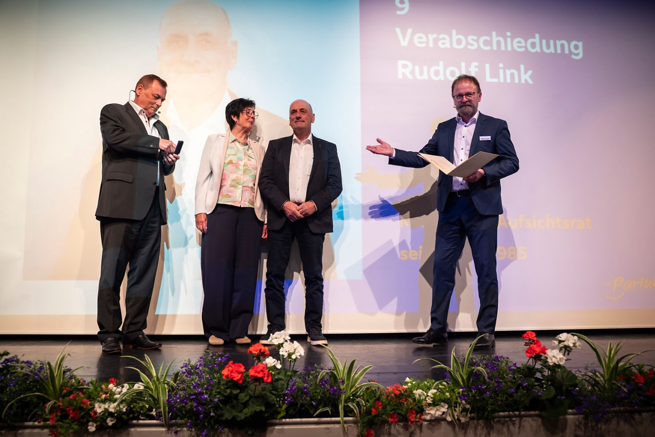 Drei Männer und eine Frau stehen vor einer Leinwand