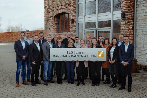 Gruppenbild vor Bankhaus mit 125 Jahre Banner
