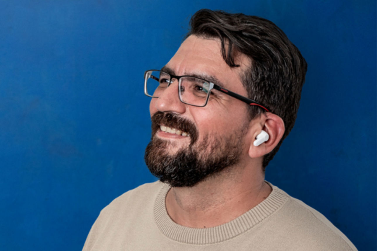 Mann mit weißen Kopfhörern vor einem blauen Hintergrund 