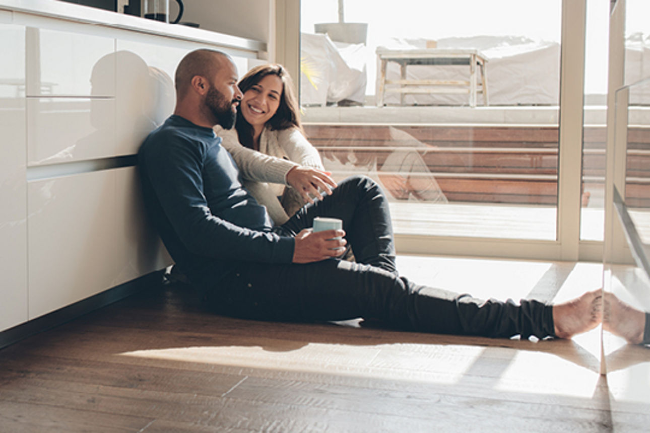 Ein Mann und eine Frau sitzen zusammen auf dem Boden einer Küche