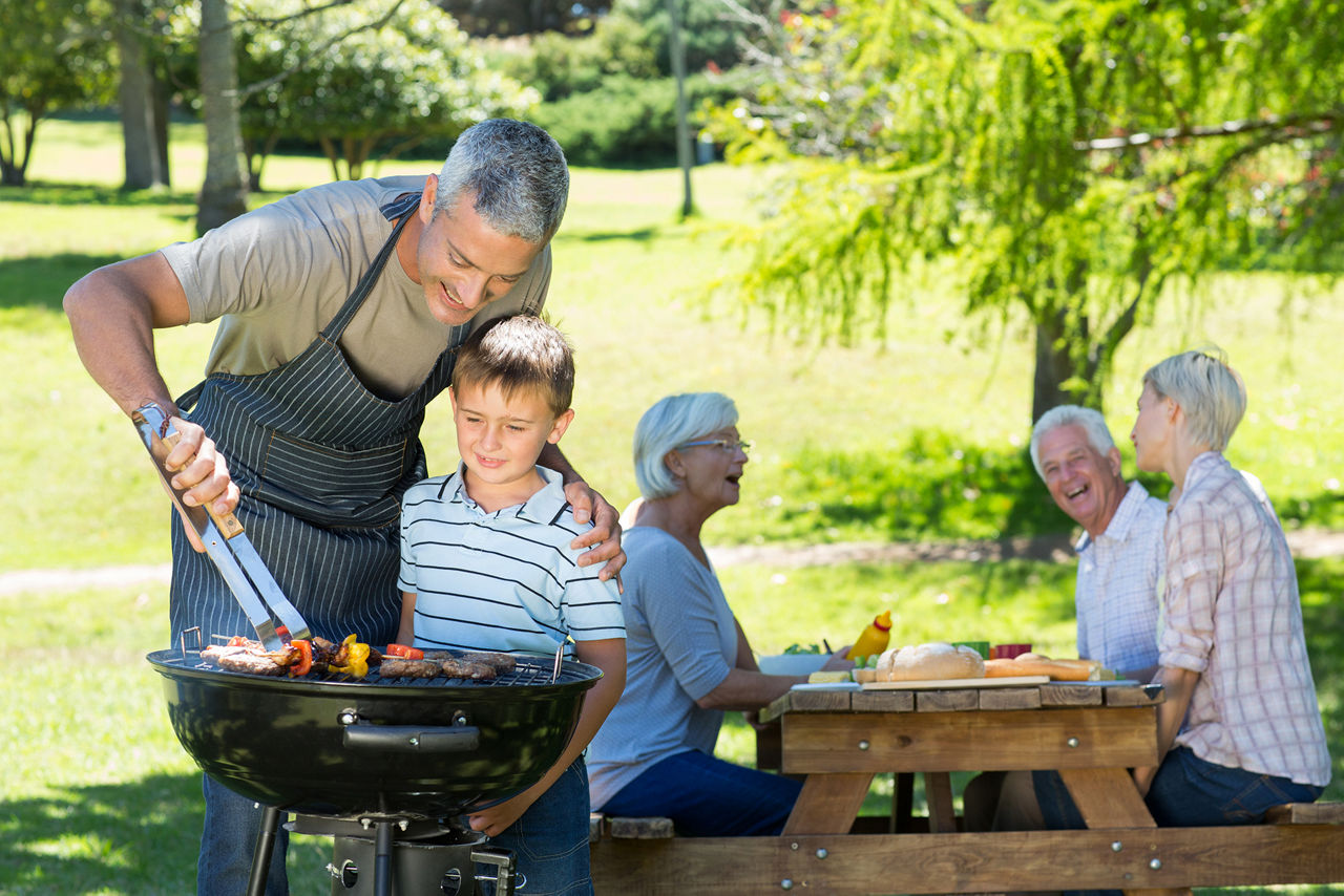 Happy father doing barbecue with his son on a sunny day