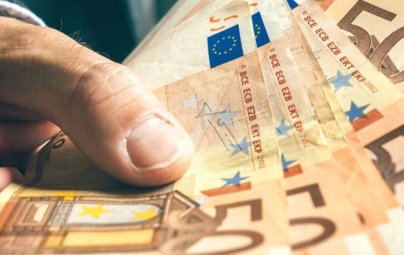 Eine Person hält einen Stapel Euro-Banknoten mit verschiedenen Stückelungen in den Händen.