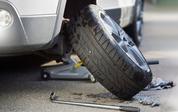 Ein Mechaniker benutzt einen Schraubenschlüssel, um einen Autoreifen zu reparieren