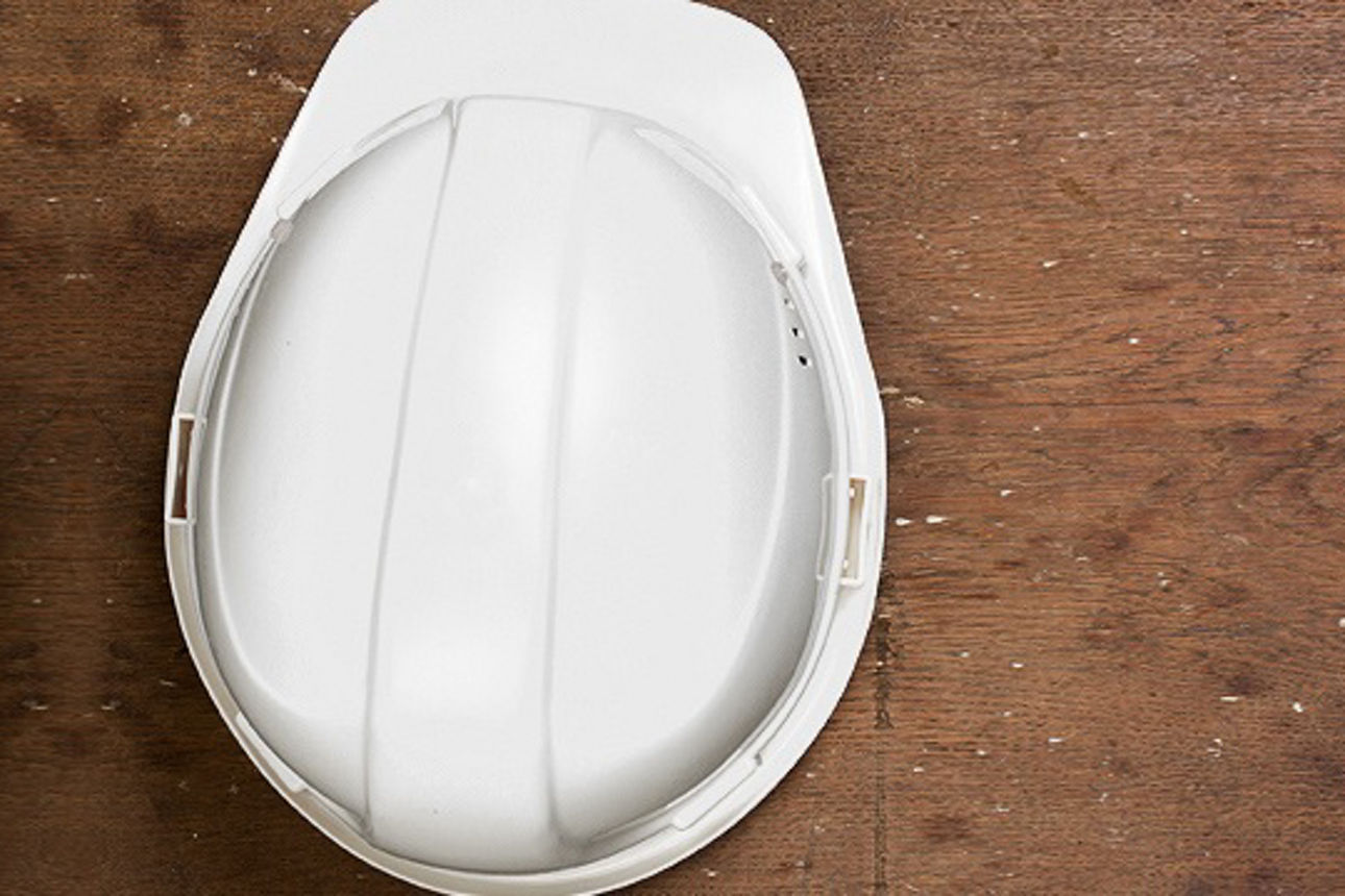 Ein weißer Schutzhelm, der auf einem Holzboden liegt