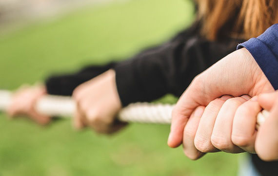 Nahaufnahme von zwei Menschen, die sich an einem Seil festhalten, als Symbol für Verbindung und Teamwork
