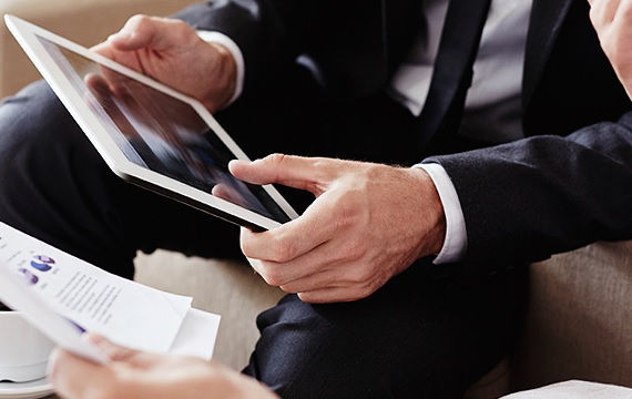 Ein Mann im Anzug hält einen Tablet-Computer und wirkt konzentriert.