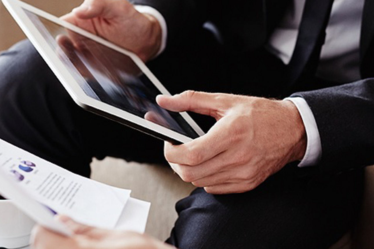 Ein Mann im Anzug hält einen Tablet-Computer und wirkt konzentriert.