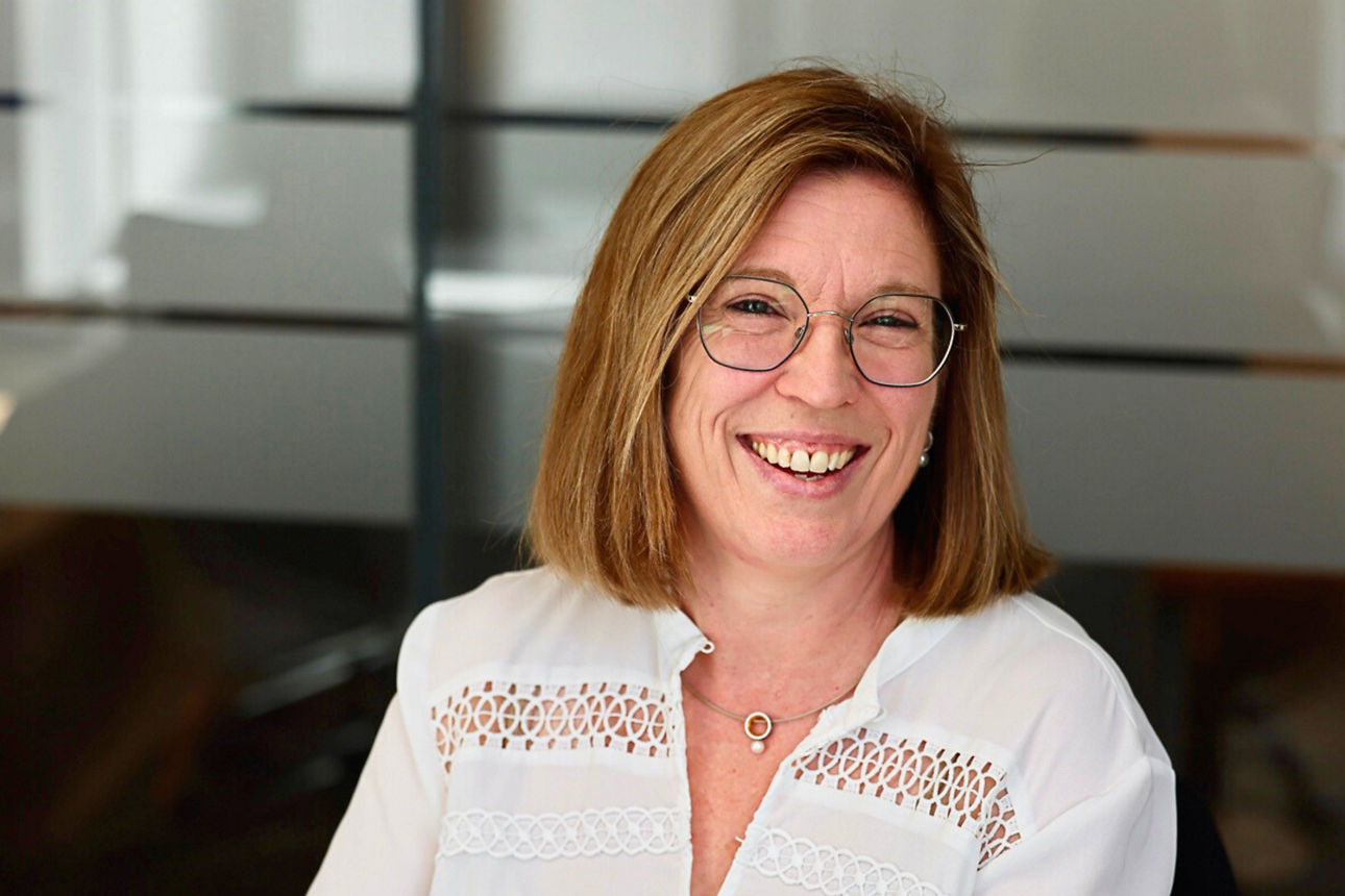 Eine lächelnde Frau sitzt an ihrem Arbeitsplatz