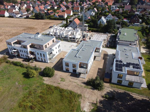 Luftaufnahme von mehreren modernen Flachdachgebäuden in einer Neubausiedlung. 