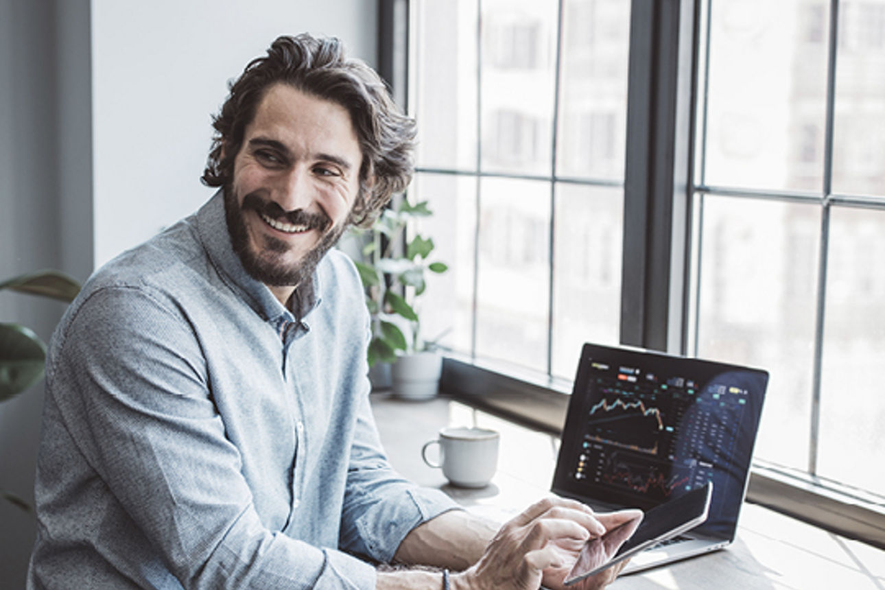 Ein Mann lächelt und tätigt an seinem Ipad seine Finanzen.