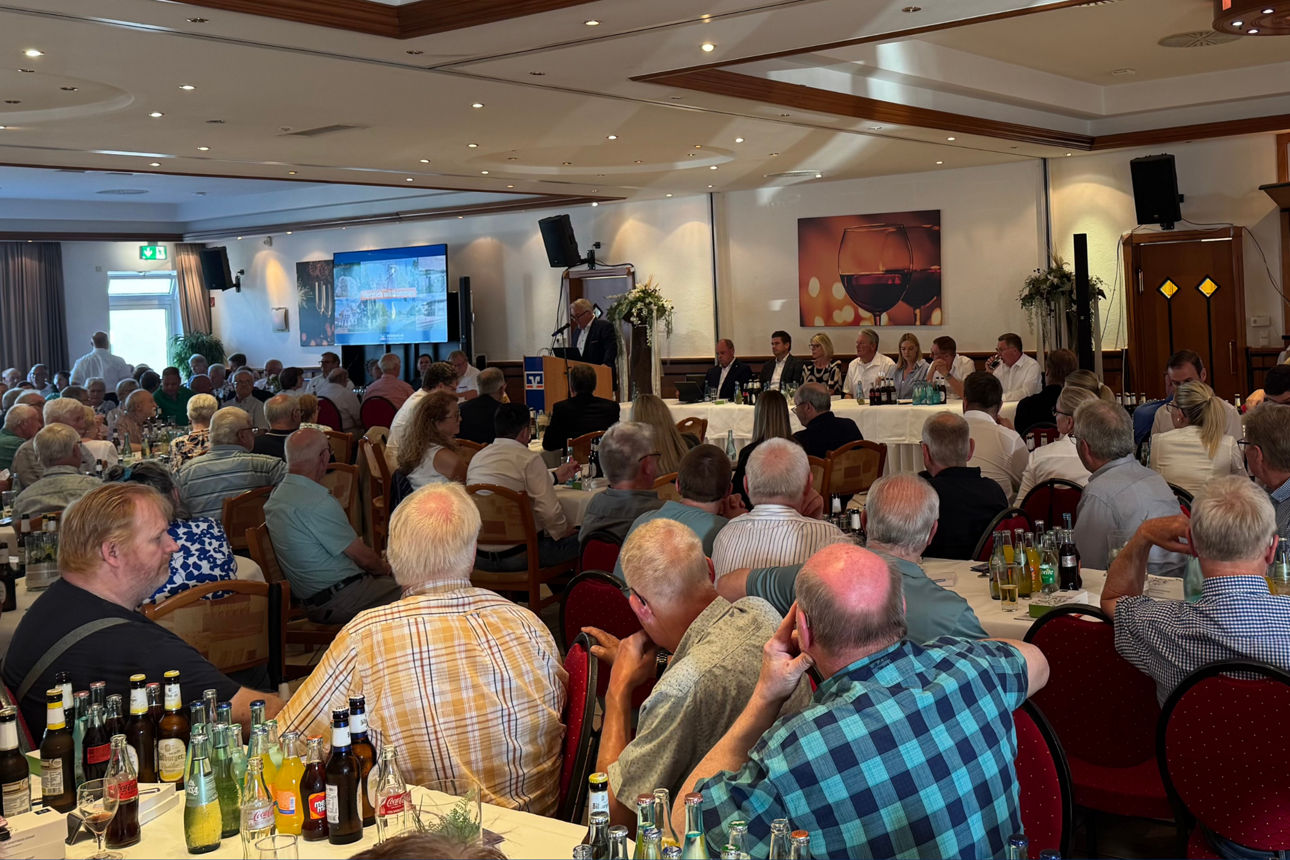 Eine große Gruppe von Menschen, die an einem Seminar oder einer Präsentation in einem Bankettsaal teilnimmt.
