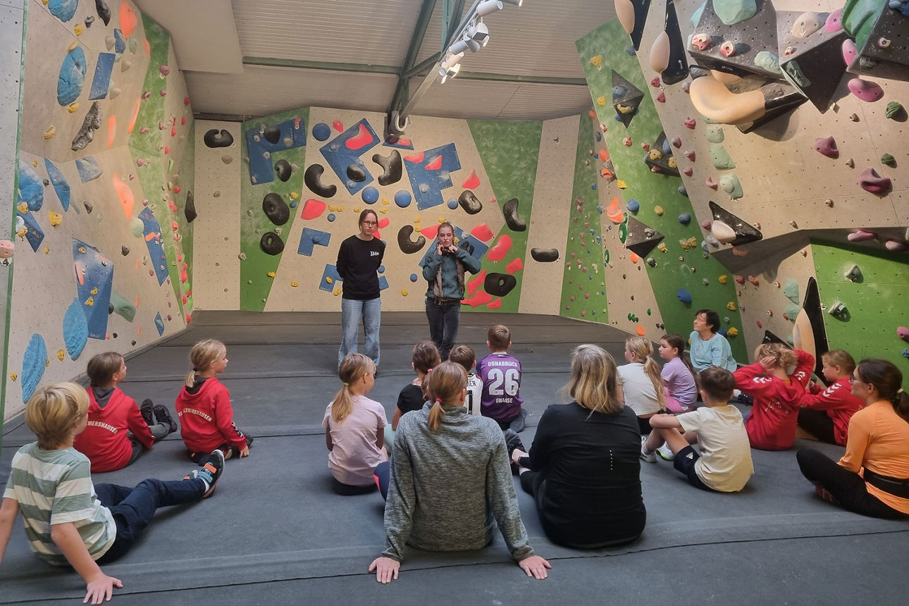 Eine Gruppe Kinder und Erwachsene wird ins Bouldern eingewiesen