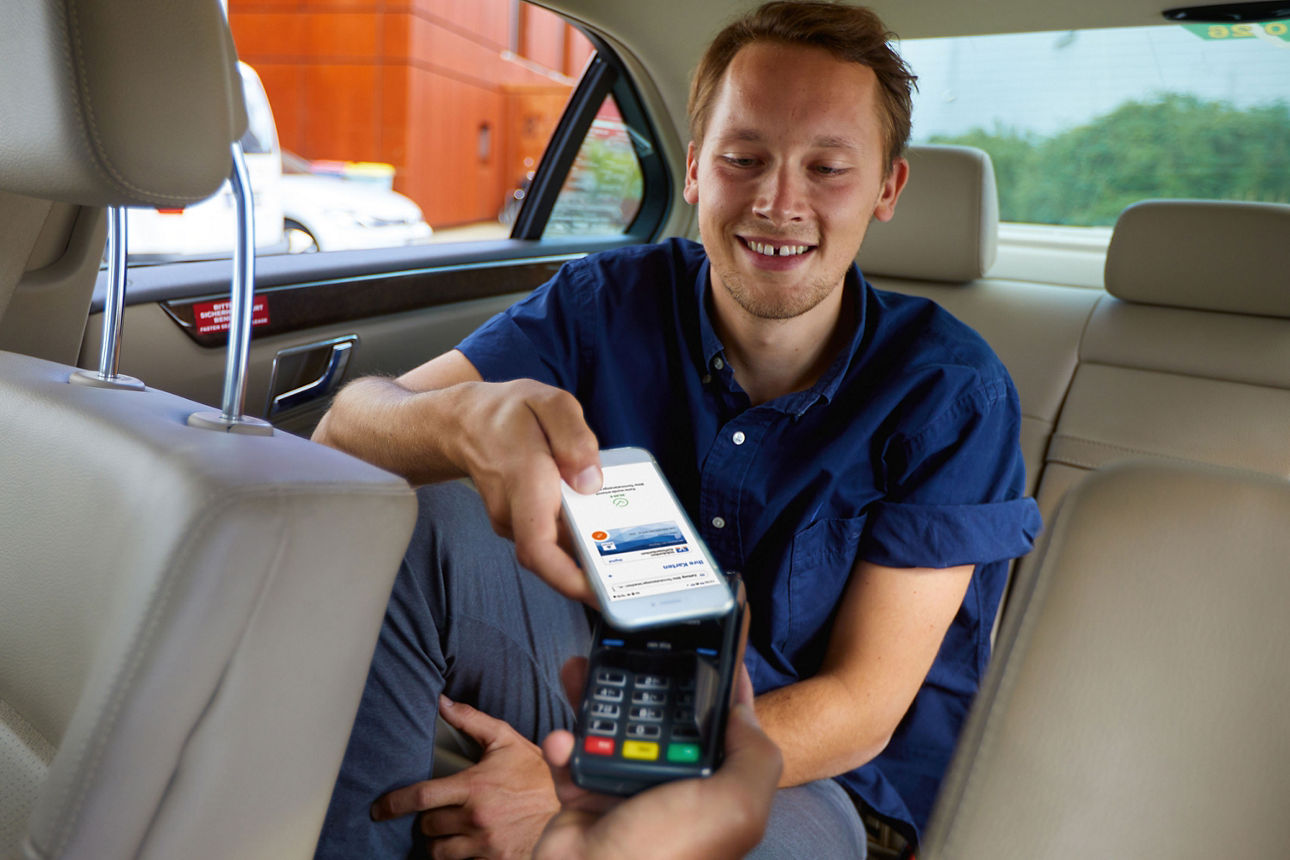 Ein Mann bezahlt im Taxi mit seinem Smartphone