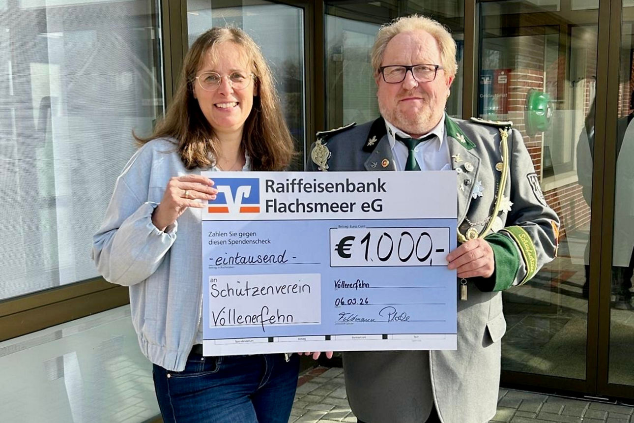 Ein Mann in Uniform und eine Frau präsentieren draußen stolz einen Scheck über 1.000 Euro