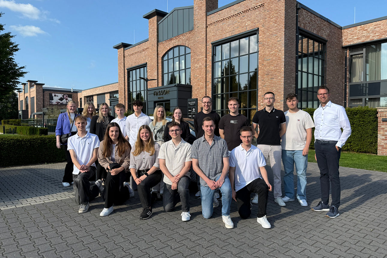 Eine Gruppe junger Berufstätiger posiert vor einem modernen Backsteingebäude.