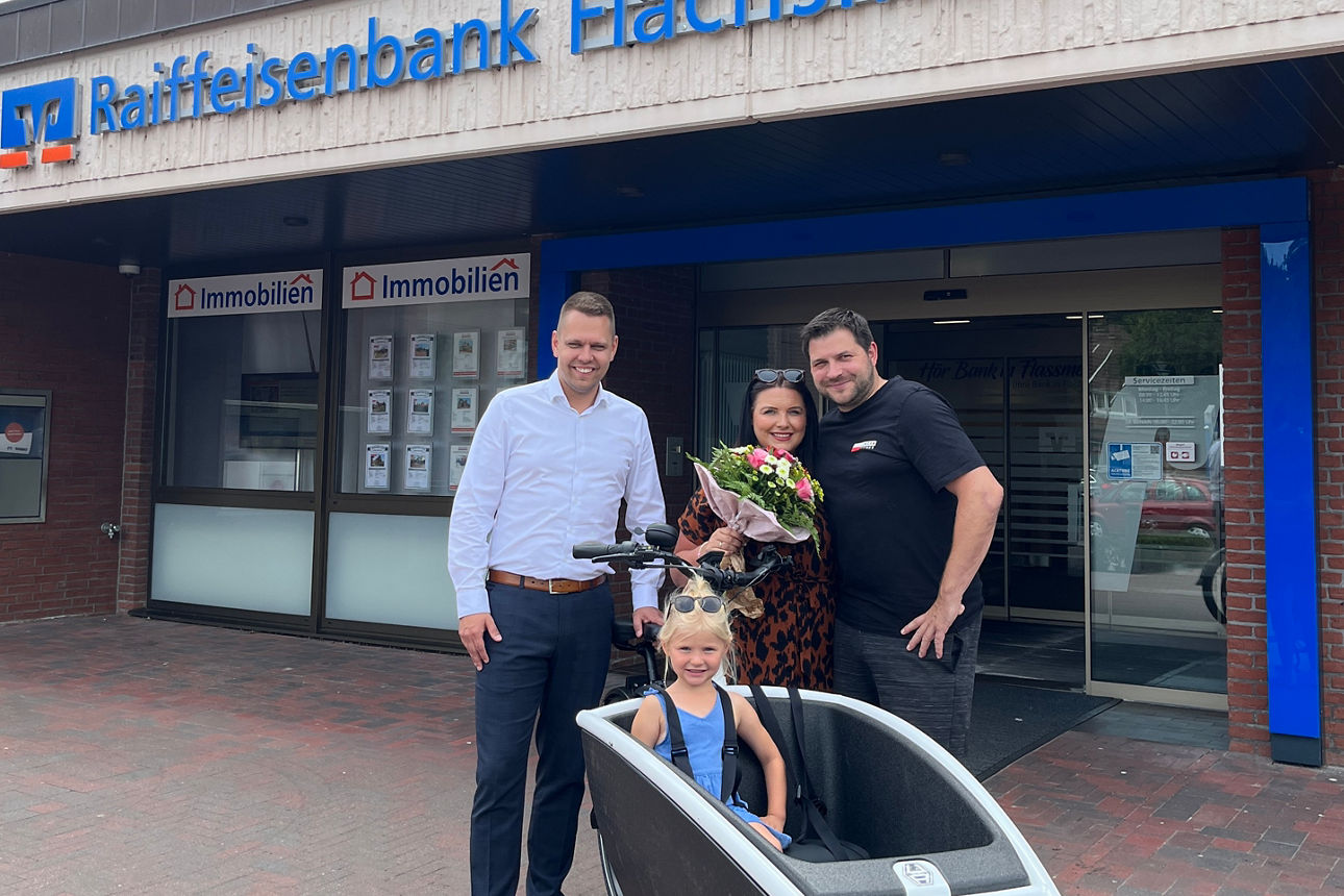 Eine Gruppe posiert vor einer Bank, um einen besonderen Anlass zu feiern.