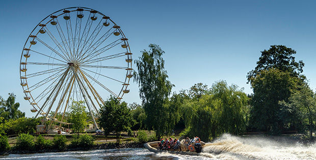 Quelle "Serengeti Park Hodenhagen" - Bild vom Park mit Riesenrad und einem kleinen, schnellen Boot auf einem See