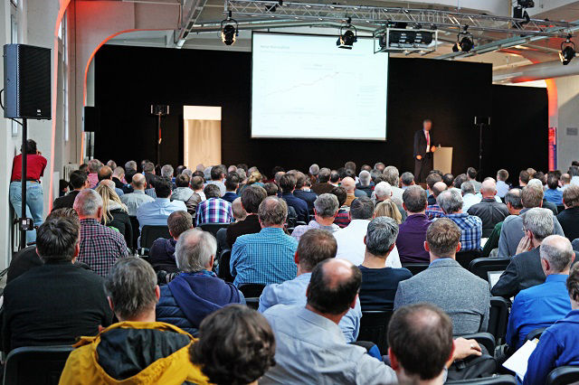 Sitzende Menschen im Saal schauen auf eine Leinwand