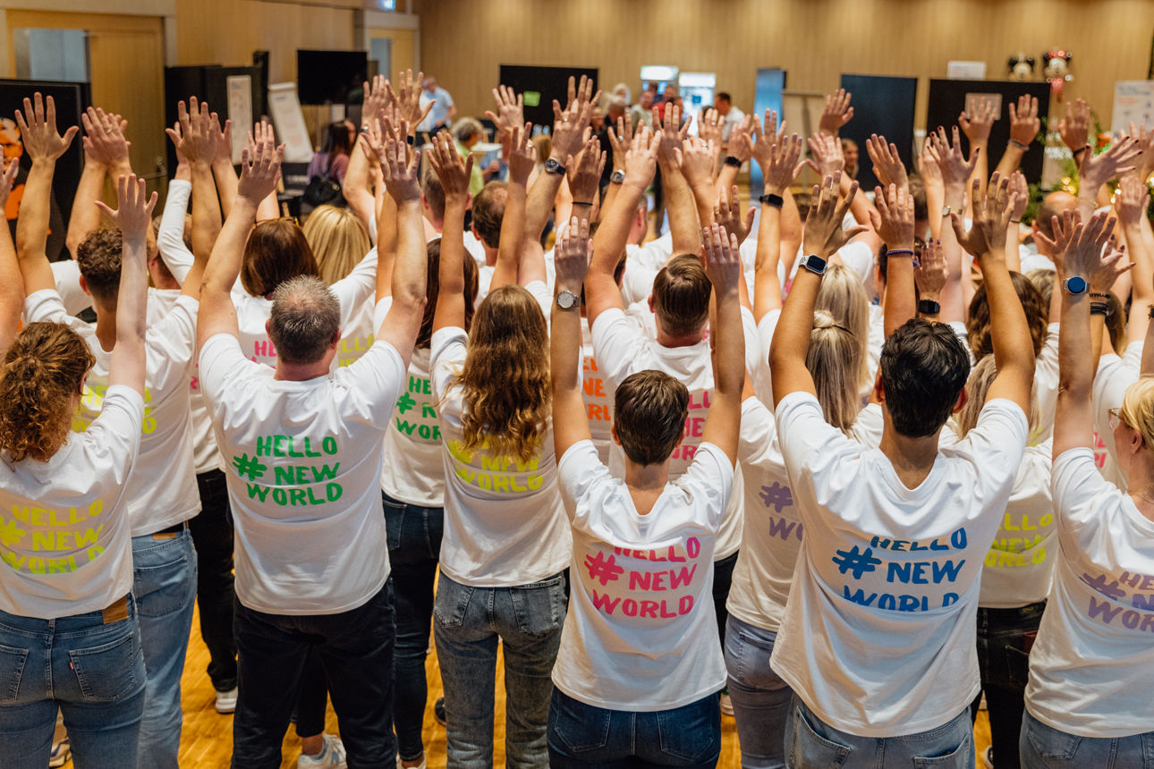 Viele Menschen stehen mit dem Rücken zur Kamera und strecken Ihre Hände nach oben