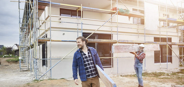 Zwei Männer auf Baustelle vor Rohbau