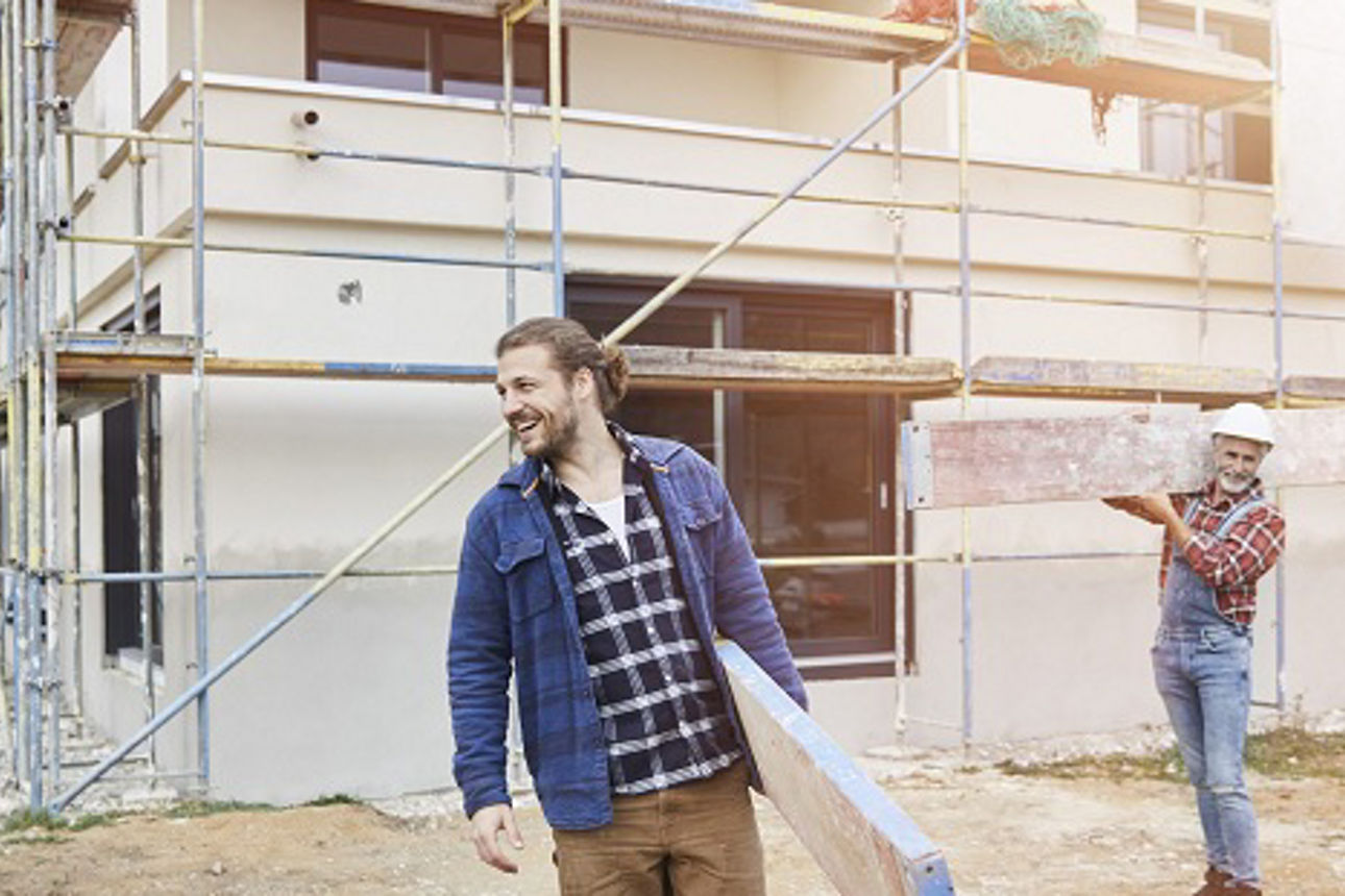  Zwei Männer auf Baustelle vor Rohbau