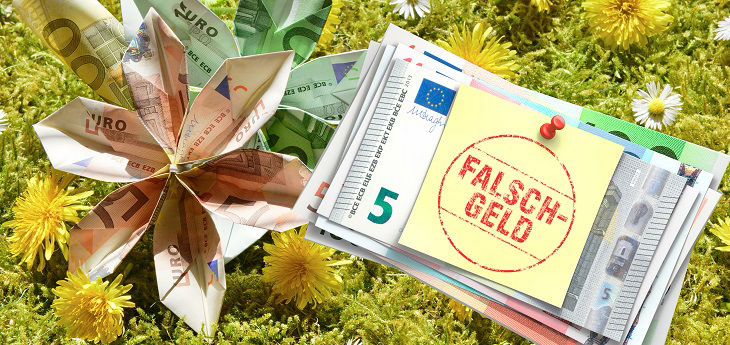 Falschgeldbündel mit gelbem Post-it auf dem Falschgeld steht auf Wiese