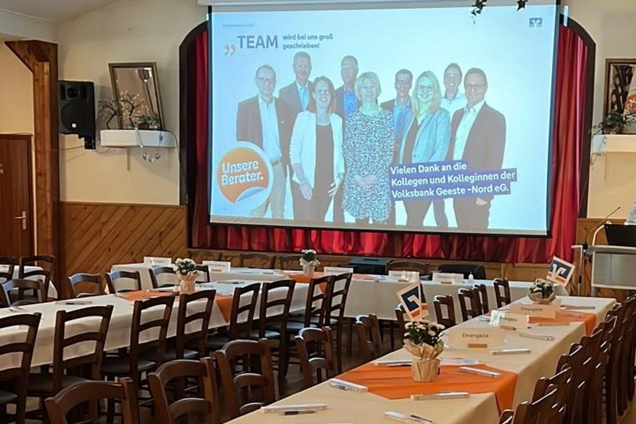 Räumlichkeit der Generalversammlung, gedeckte Tischreihen und eingeschaltete Bildschrimpräsentation