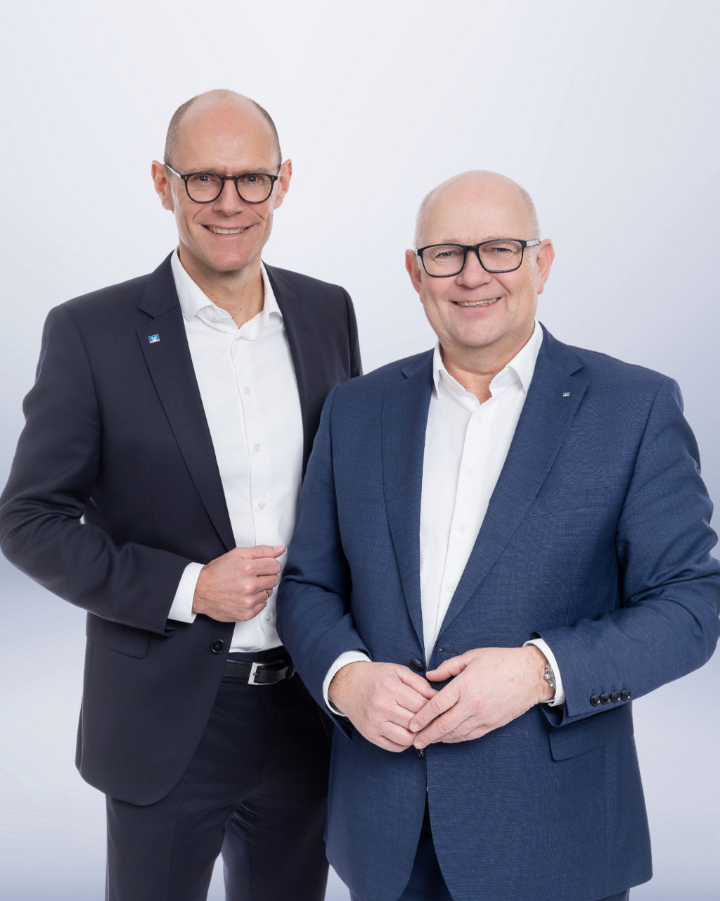 Zwei Männer in Anzügen lächeln in die Kamera.