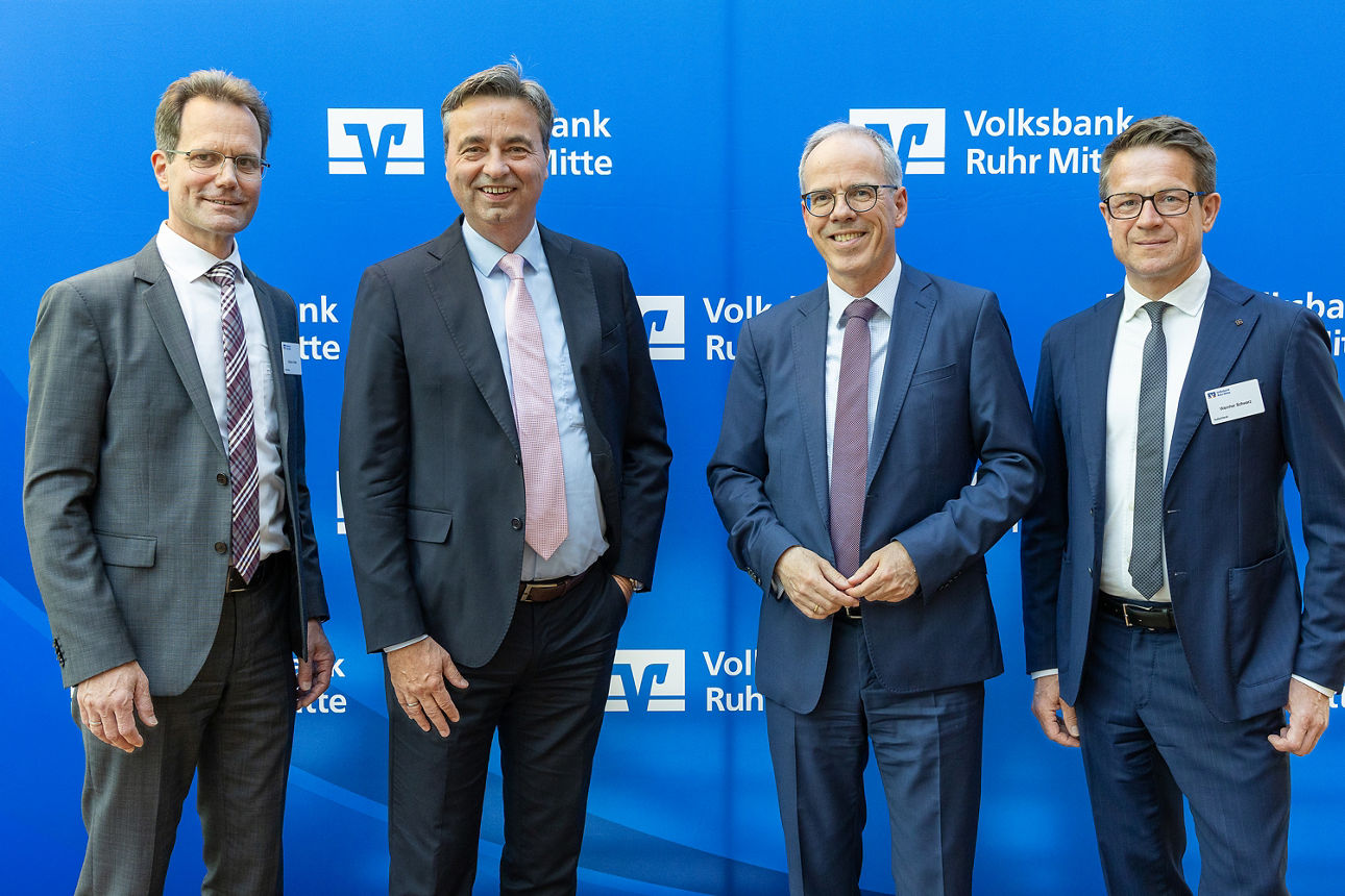Vor einer Pressewand stehen vier Personen. Zwei Männer aus dem Aufsichtsrat der Volksbank Ruhr Mitte und die beiden Vorstände.