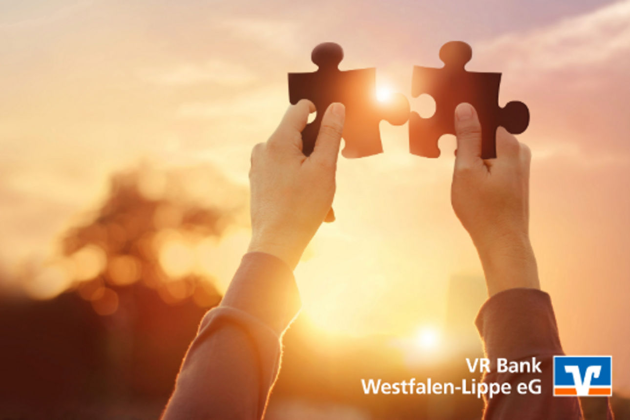 Zwei Puzzleteile werden in die Luft gehalten und zusammengesteckt