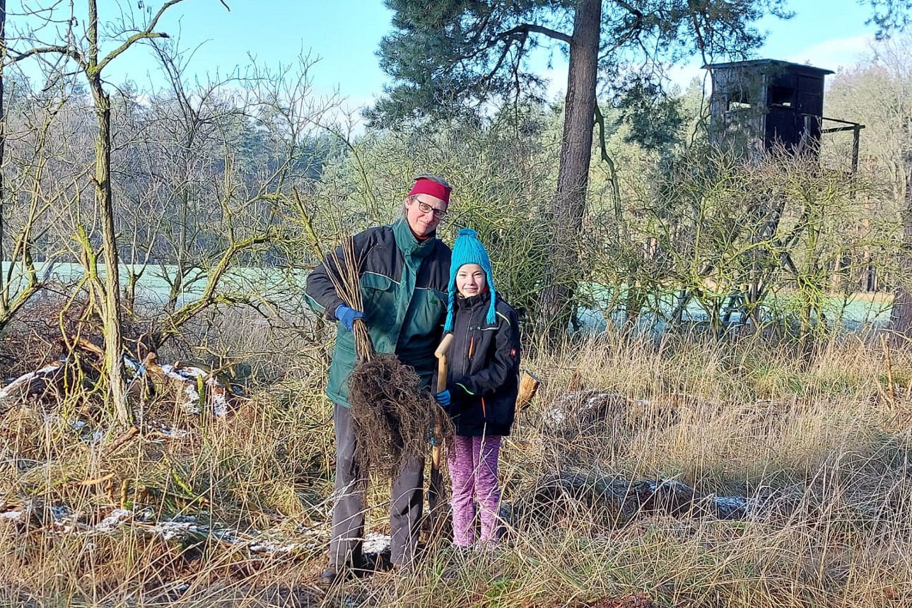 Eine Mitarbeiterin und ihre Tochter mit einem Sätzling in der Hand.