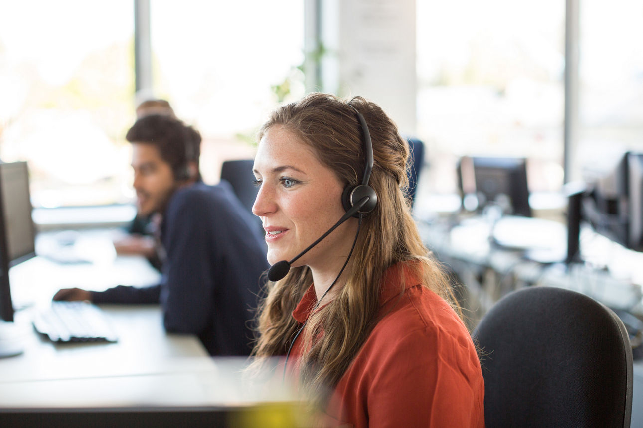Smiling female customer representative wearing headphones working in office