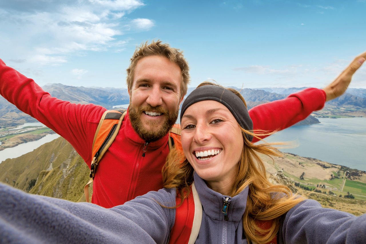 Ein Mann und eine Frau in Wanderkleidung stehen auf einem Berggipfel