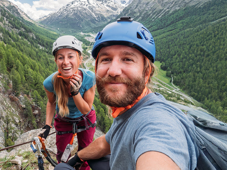 Zwei Menschen in Kletterkleidung auf einem Berg lächeln in die Kamera
