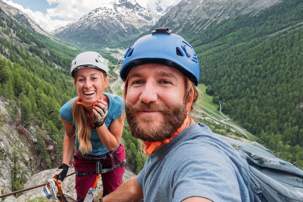 Zwei Menschen in Kletterkleidung auf einem Berg schauen in die Kamera