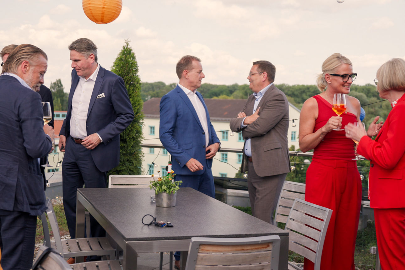 Ausschnitt einer Dachterrassen-Party, Einige gut gekleidete Business-Leute stehen plaudernd  zusammen