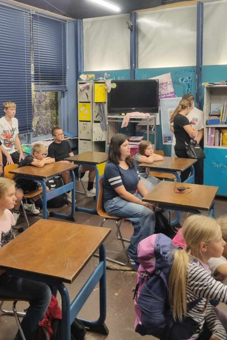 Kinder sitzen an Tischen eines Filmset-Klassenzimmers