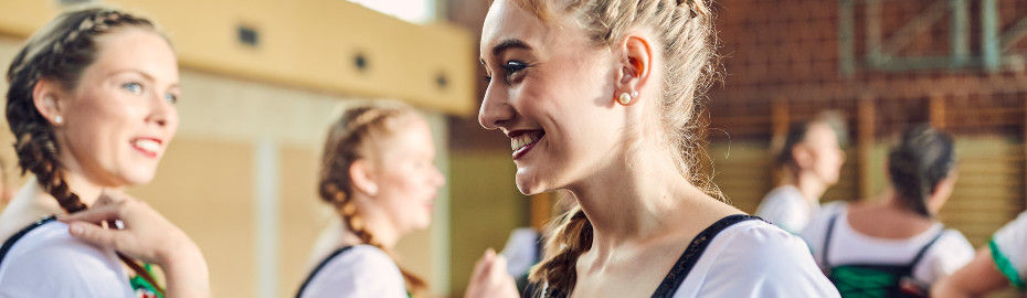 Junge Frauen mit Trachten in einer Sporthalle