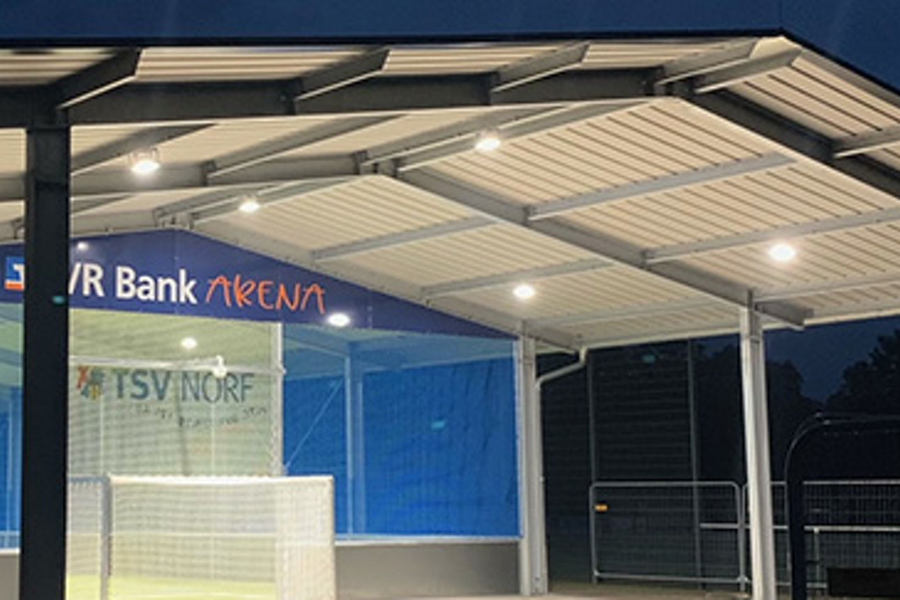 Eine moderne, gut beleuchtete Sporthalle bei Nacht.