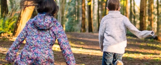 Kinder, Junge und Mädchen laufen im Wald