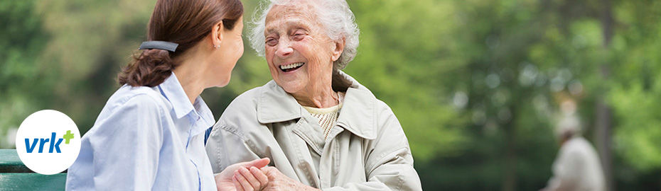 Eine alte und eine junge Frau lächeln sich an