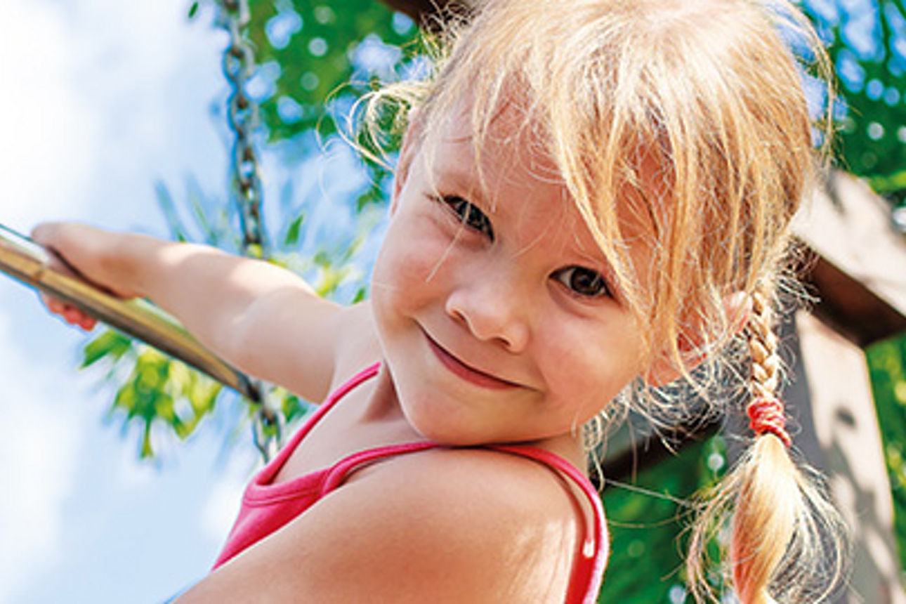 Ein kleines Mädchen mit blondem geflochtenem Haar, das in die Kamera lächelt