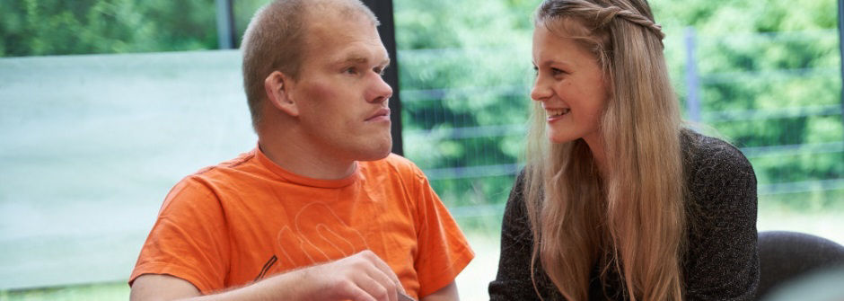Pflegerin trainiert mit Mann im orangenen T-Shirt