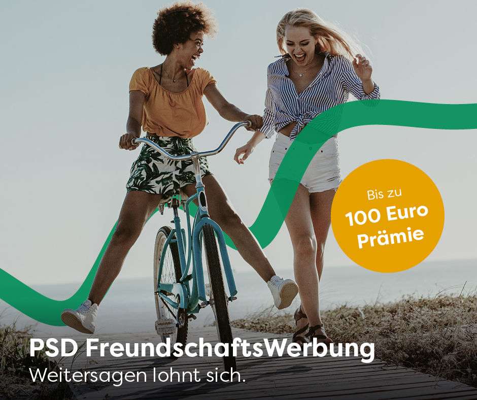 Eine junge Frau auf einem Fahrrad und eine junge Frau zu Fuß gehen am Strand spazieren