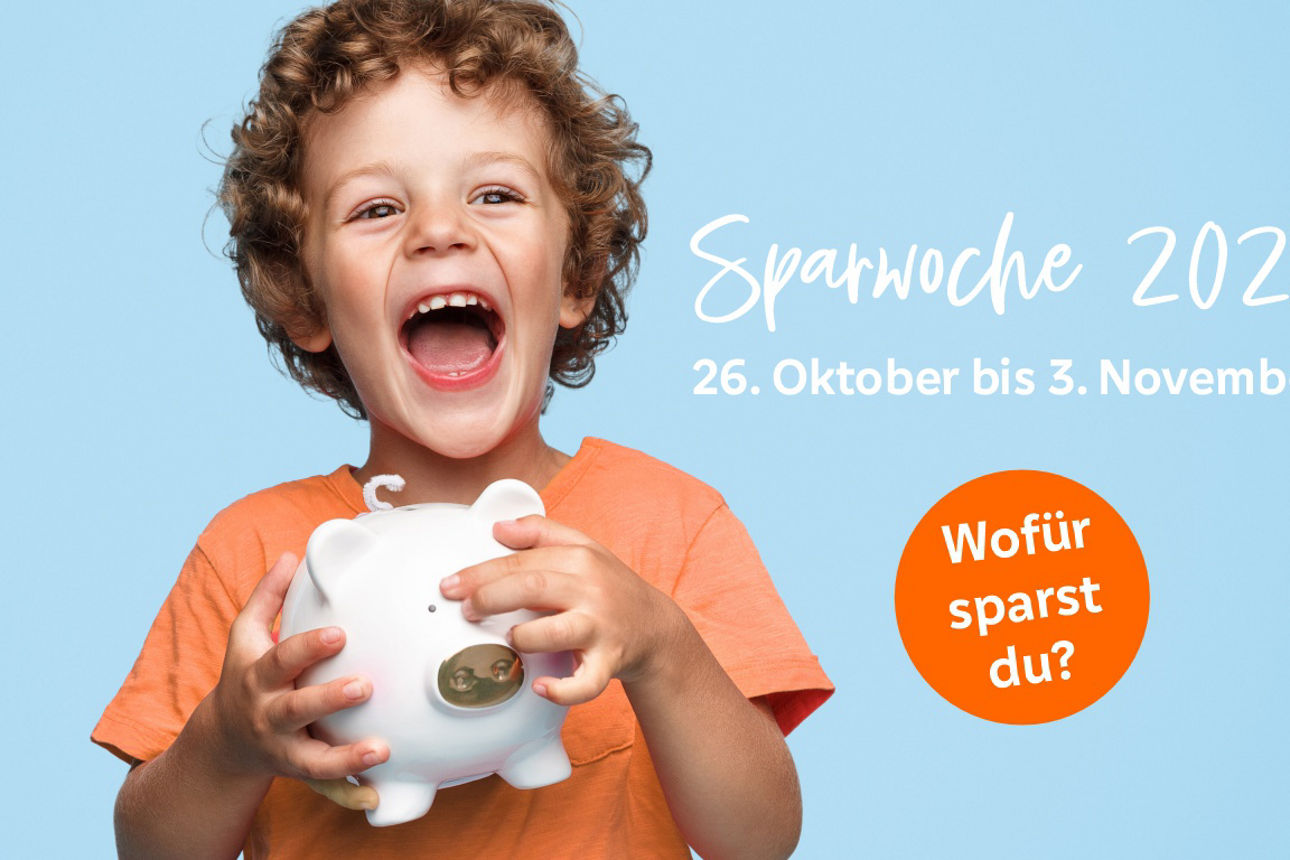 Ein kleiner Junge hält ein weißes Sparschwein in den Händen und lacht.