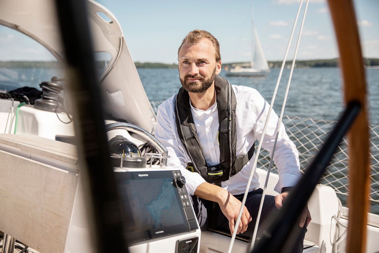 Mann sitzt auf einem Segelboot und schaut in den Horizont.