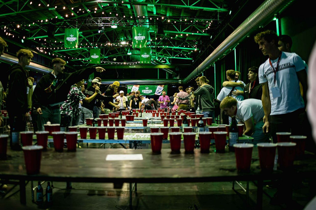 Das Bild zeigt die Halle alte Schlosserei im Tonwerk Dorfen mit Tischen und vielen Menschen die Beerpong spielen.