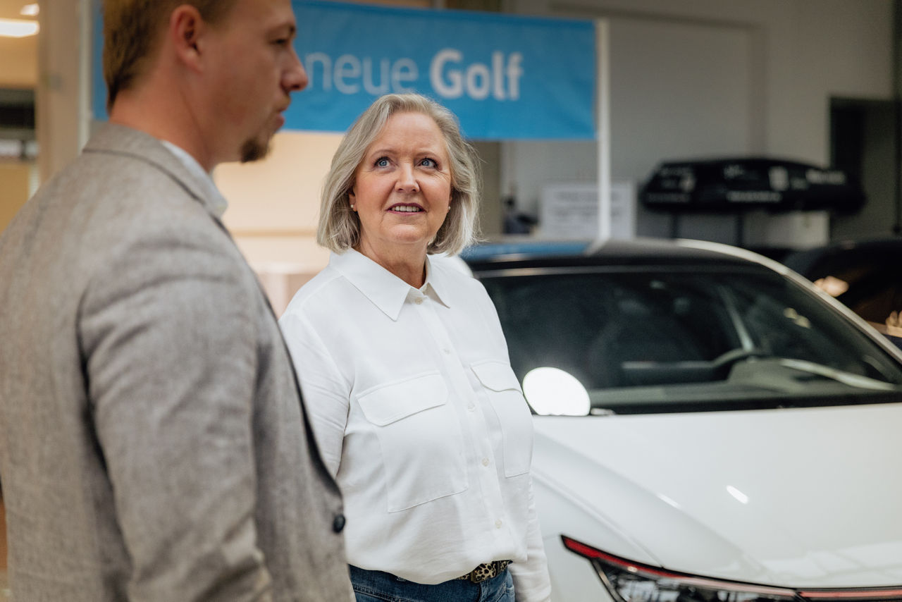 Berater Florian Abschütz und Ulrike Kehm befinden sich in einer Beratungssituation im Verkaufsraum des „Autohaus Kehm“ vor einem ausgestellten Fahrzeugmodell. Das Bild zeigt den offenen Showroom‑Bereich mit Fahrzeugpräsentation und Beratungsumgebung