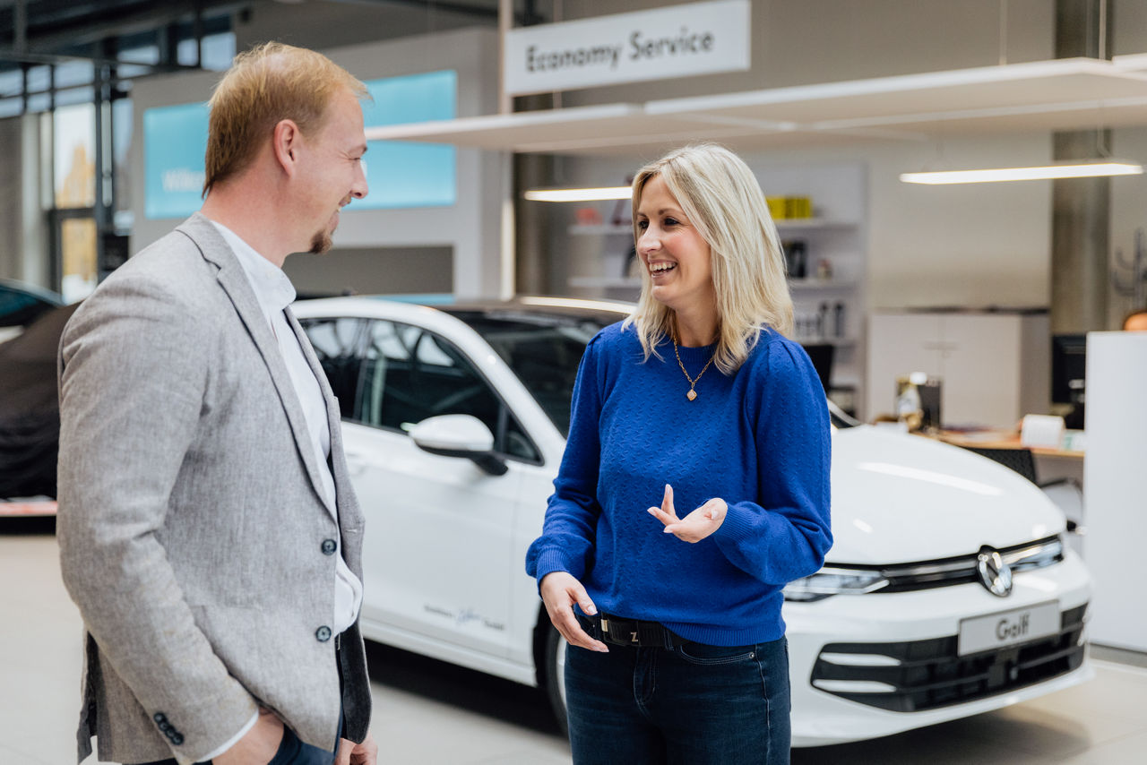 Berater Florian Abschütz und Lisa Woytinnek befinden sich im Showroom des „Autohaus Kehm“. Im Hintergrund sind mehrere Ausstellungsfahrzeuge sowie angrenzende Service‑ und Beratungsbereiche des Autohauses sichtbar, die den Verkaufs‑ und Kundenbereich abbilden